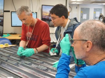 Three researchers analysing different sized rocks 